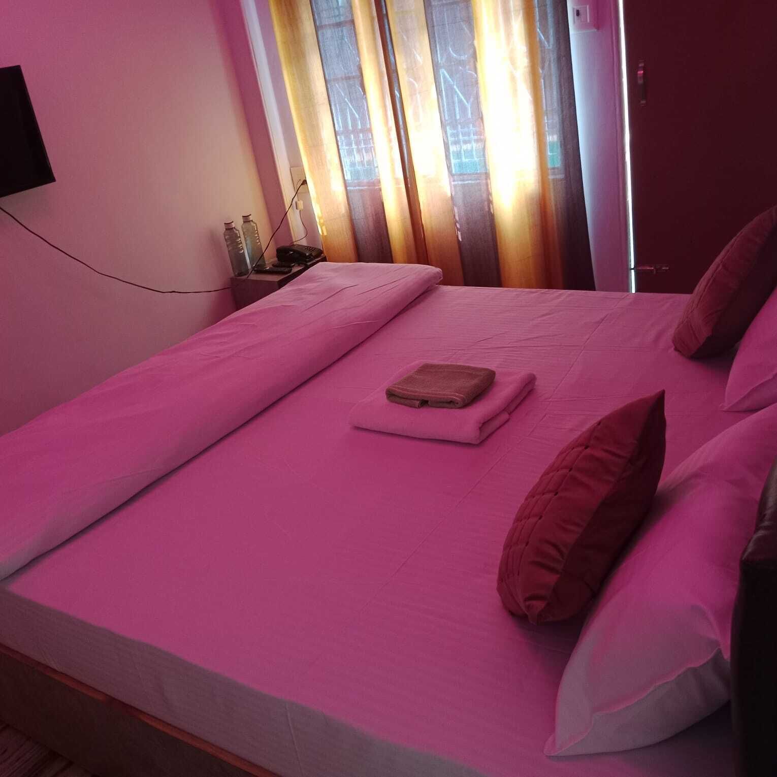 Une chambre avec un lit, une table de chevet et une fenêtre avec des rideaux.
