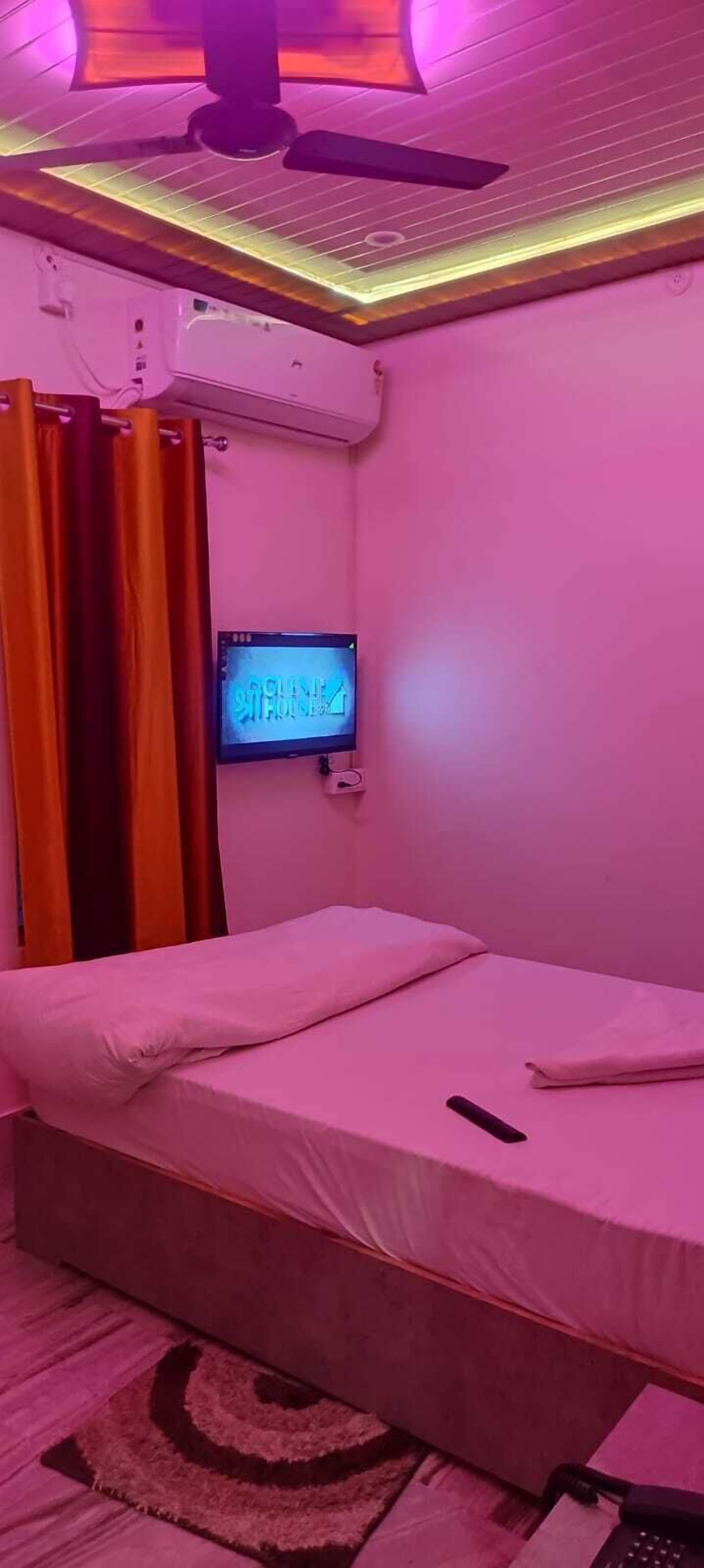 Ein Zimmer mit einem Bett, einem Fernseher und einem Deckenventilator.