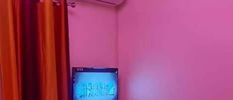Ein Zimmer mit einem Bett, einem Fernseher und einem Deckenventilator.
