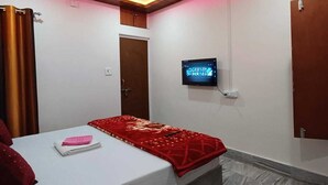A bedroom with a bed, a television, and a ceiling fan. - Shree Guest House (Varanasi)