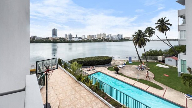 Un espace piscine offrant une vue sur une étendue d’eau paisible et, au loin, sur le panorama de la ville.