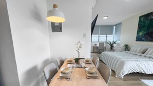 A modern hotel room with a dining area, a bed, and a large window. - La Rada 222 | Studio Apt in San Juan With Views (San Juan)