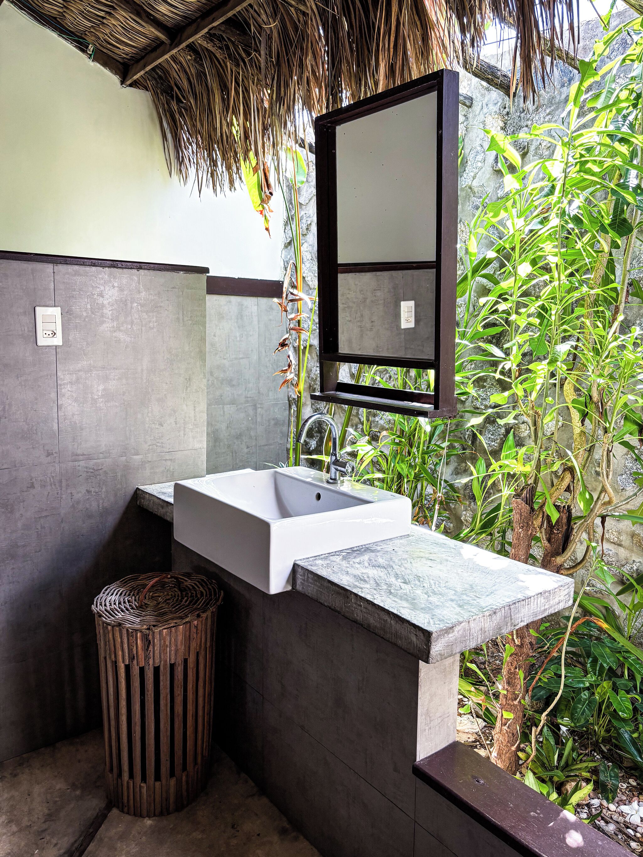 Une salle de bain avec un lavabo blanc, un miroir et une poubelle.