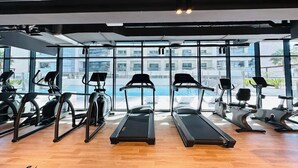A gym with treadmills, elliptical machines, and stationary bikes arranged in rows. - Bloomfields Stylish 1Br Binghatti Creek (Dubai)