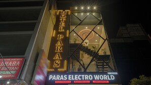 Un hotel llamado 'Hotel Paras' con un letrero de neón, una escalera y un cartel que dice 'Paras Electro World' debajo.
