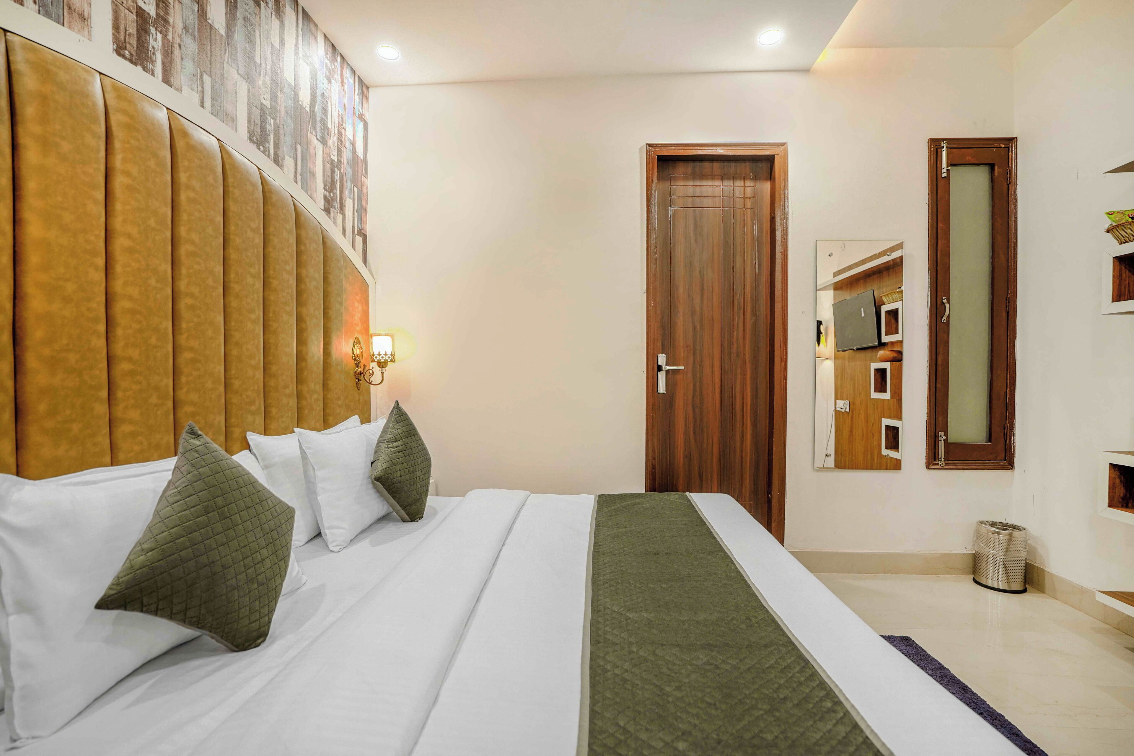 Camera d'albergo con un letto grande, una testiera, una porta in legno e un cestino dei rifiuti.