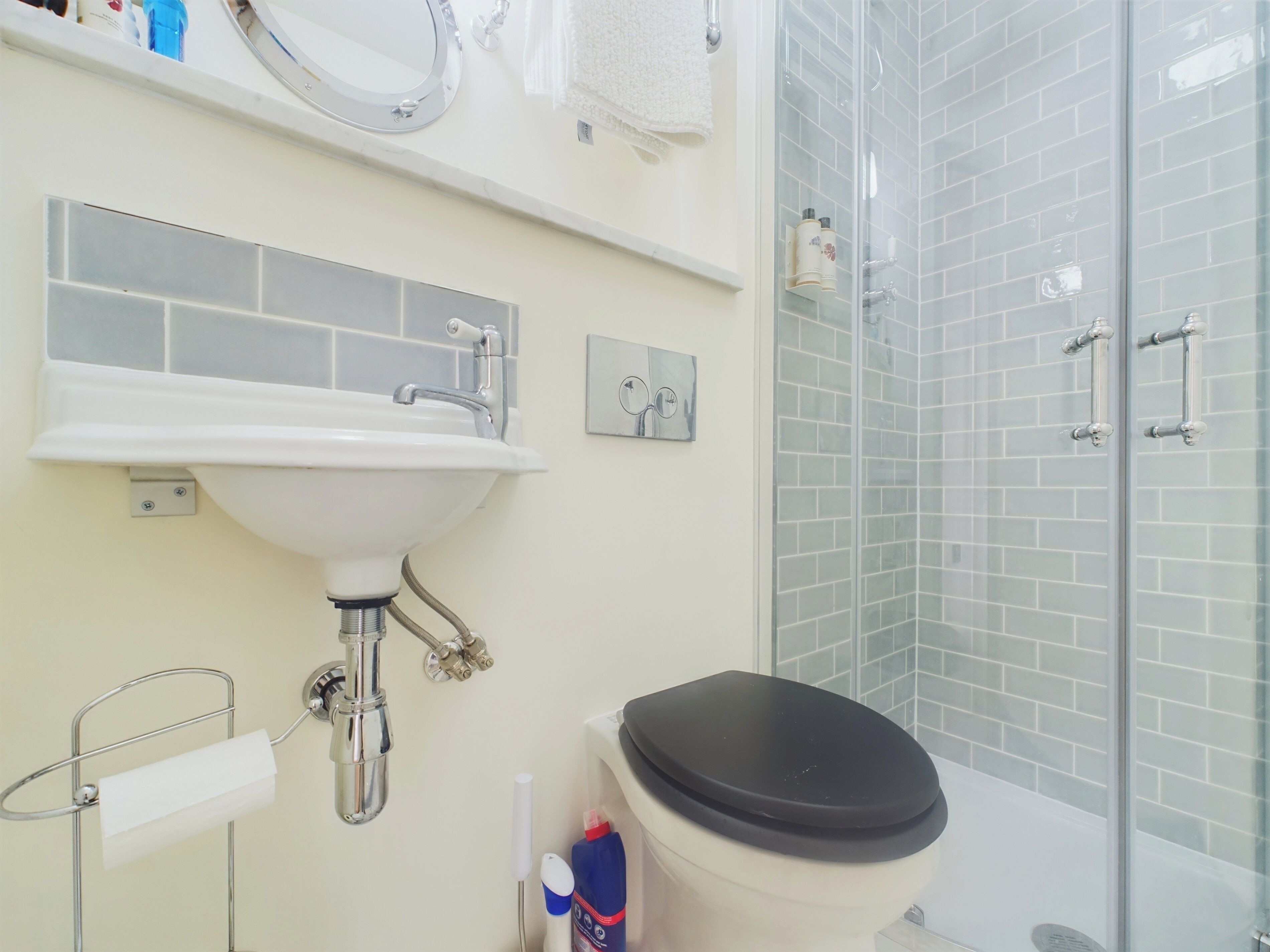 Et badeværelse med en hvid vask, toilet og en bruseniche i glas.