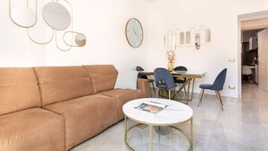 Un salon moderne avec un canapé marron, une table basse ronde et un coin repas comprenant une table blanche et des chaises bleues.