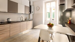 Une cuisine moderne avec des meubles en bois clair, un plan de travail blanc et un coin repas comprenant une table et des chaises blanches.