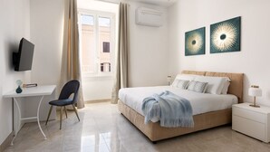 Une chambre d’hôtel moderne équipée d’un lit, d’un bureau, d’une chaise et de deux œuvres d’art accrochées au mur.