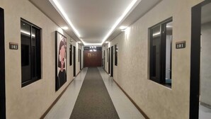 Pasillo de hotel con puertas numeradas, un corredor central y un cartel para la habitación de huéspedes.
