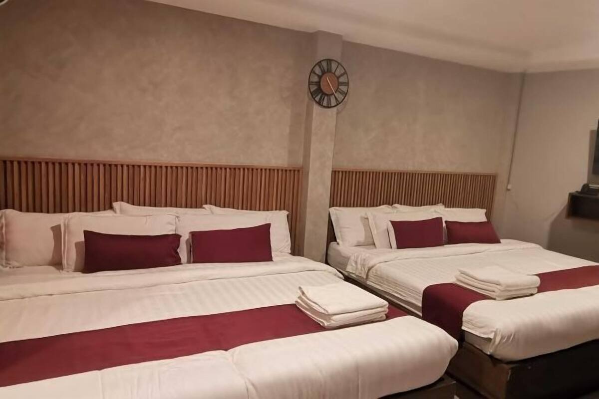 A hotel room with two beds, a clock on the wall, and a wooden headboard.