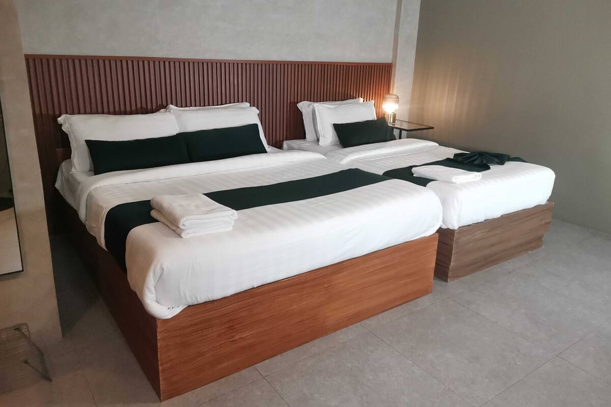 A double bed with a wooden headboard, white bedding, and a bedside table with a lamp.