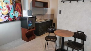 Una cocina compacta con refrigerador, lavamanos y comedor con mesa y sillas.