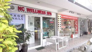 Un spa de bienestar con un cartel que dice NC WELLNESS SPA, una cafetería con un letrero rojo y asientos al aire libre.