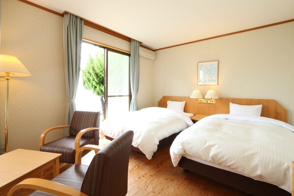 A hotel room with two beds, a desk, and a chair.