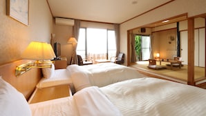 Een hotelkamer met twee bedden, een bureau, een stoel en een zithoek met een tafel en stoelen.
