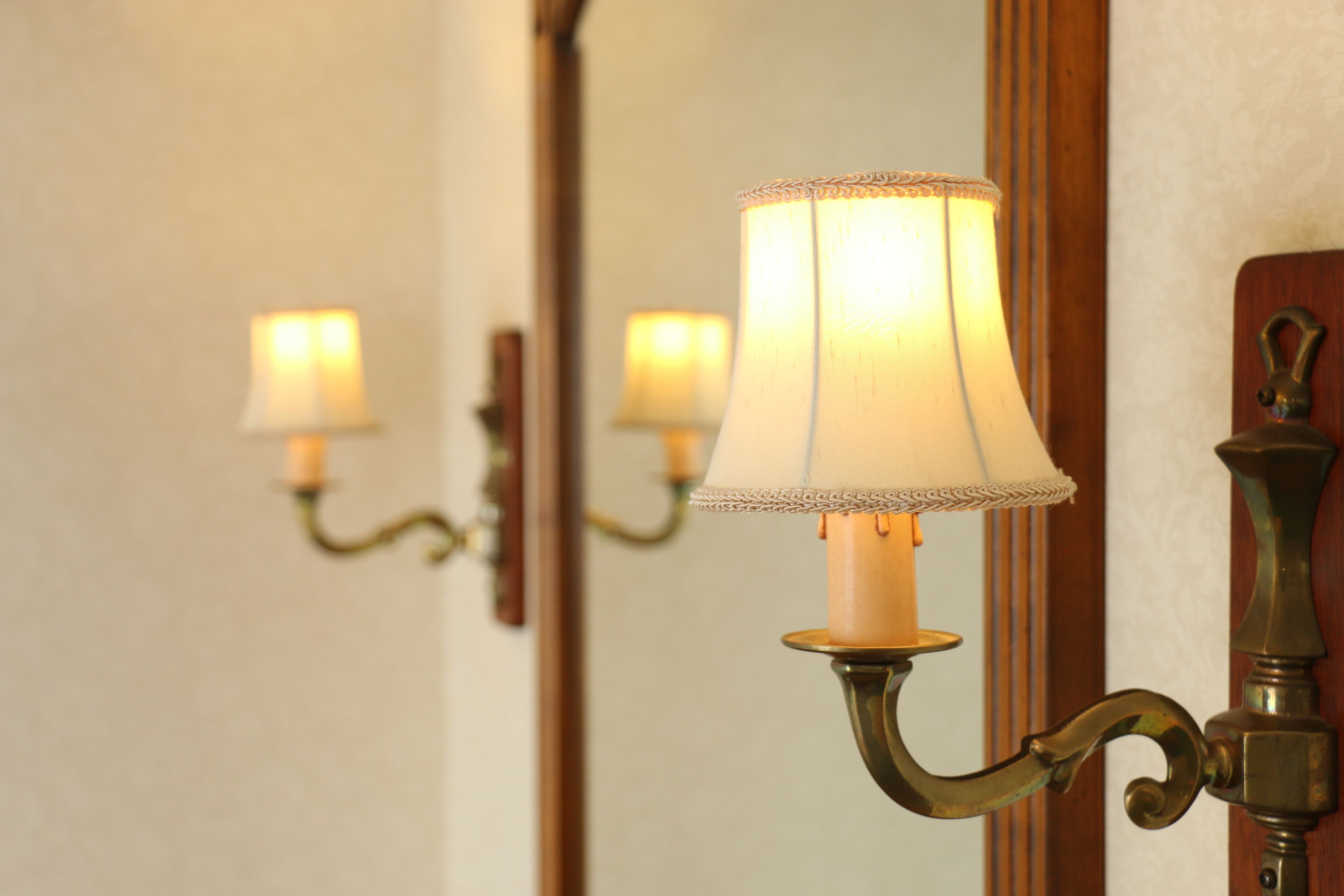 A wall-mounted lamp with a white lampshade and a brass base.