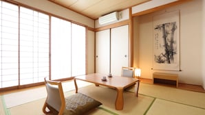 Een traditionele Japanse kamer met tatami vloeren, een lage tafel, stoelen en een schuifdeur.