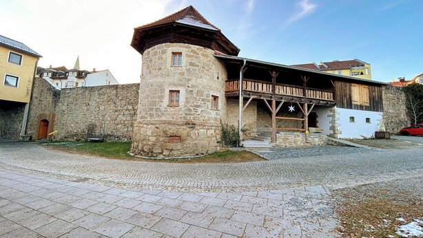 Un bâtiment historique en pierre, doté d’un balcon en bois et d’une tour en pierre.