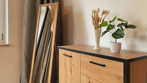 Un meuble en bois avec deux tiroirs et un vase orné de plantes sur le dessus.