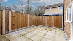 A patio area with a wooden fence, a tiled floor, and a house in the background. - 3-Bed House – Ideal for Contractors and Families (Bulwell)