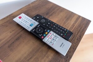 Three remote controls on a wooden surface.