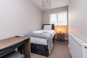 A small, neatly arranged bedroom with a bed, bedside table, and a desk. - 3-Bed House – Ideal for Contractors and Families (Bulwell)