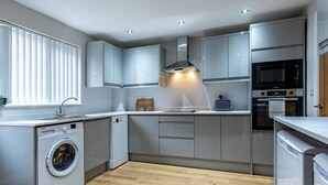 A modern kitchen with built-in appliances, a washing machine, and a microwave. - 3-Bed House – Ideal for Contractors and Families (Bulwell)