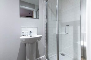 A bathroom with a white sink, mirror, and glass shower enclosure.