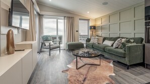 A modern living room with a green sofa, a round coffee table, and a leather rug. - Lodge No 25 | St Andrews Lodge Park (Strathkinness)