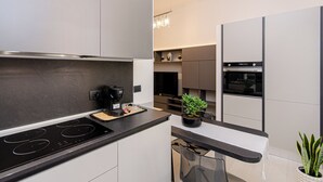 Una cocina moderna con estufa integrada, una cafetera y un pequeño comedor con mesa y sillas.