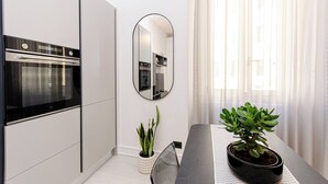 Una cocina moderna con horno integrado, un espejo y un comedor con planta en maceta.
