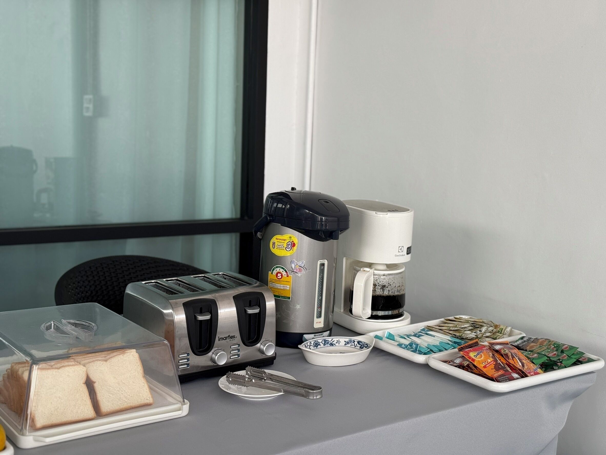 A kitchenette with a toaster, coffee maker, and a plate of snacks.