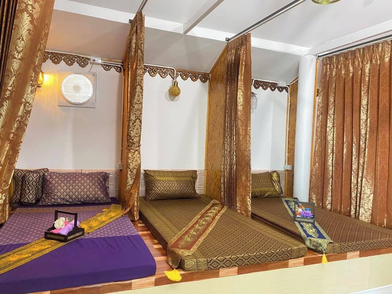 A room with two beds, each with patterned bedding and pillows, a small table with a decorative item, and a mirror reflecting the room.