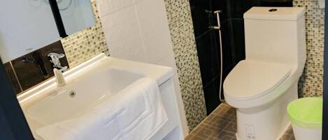 Un baño con lavamanos blanco, inodoro y zona de ducha.