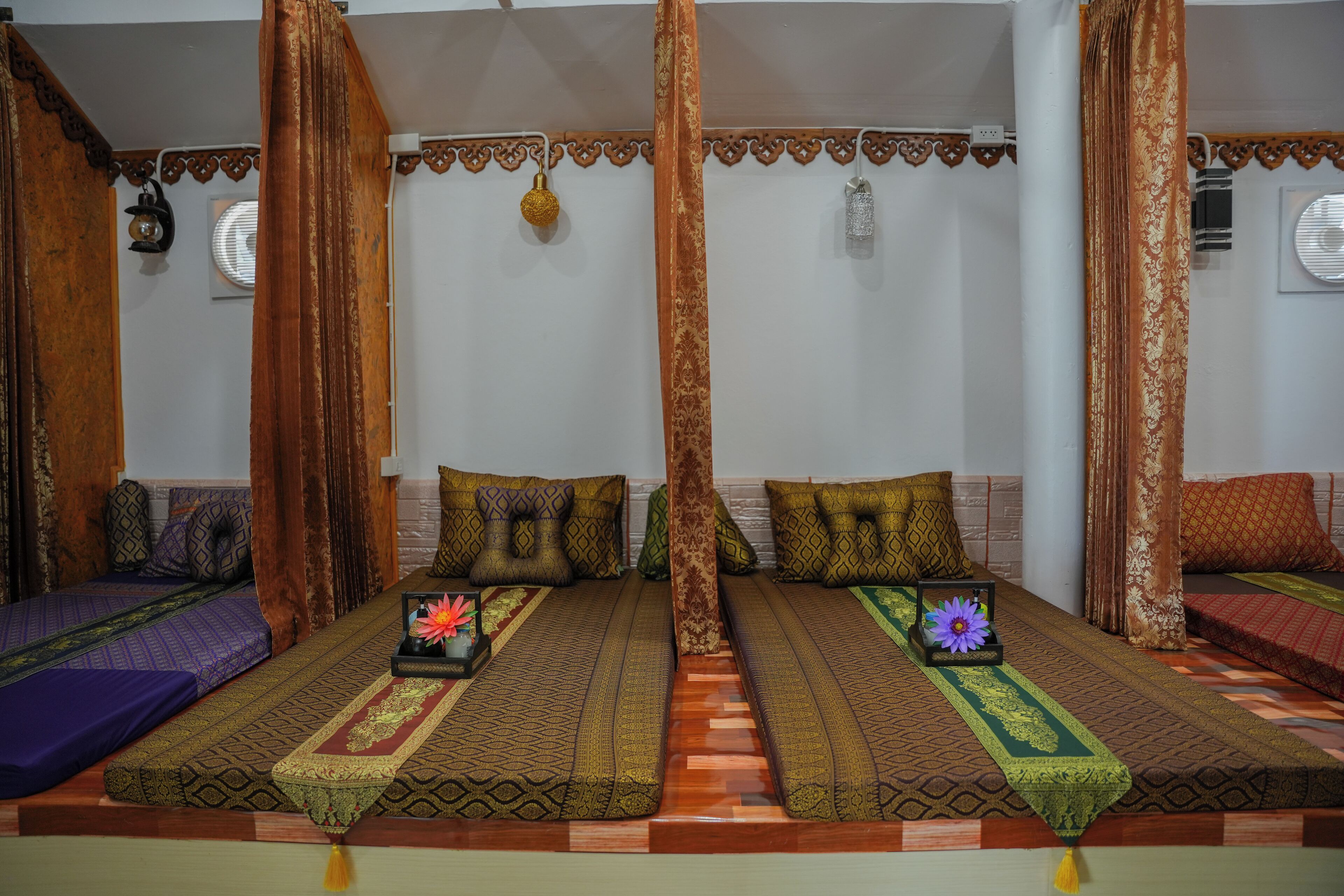 A room with three beds, each with patterned bedding and pillows.