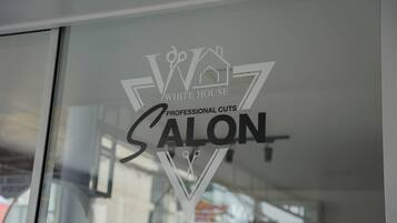A logo on a glass window with the text "White House Salon" and "Professional Cuts."