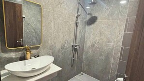 A modern bathroom with a white sink, gold faucet, and a large mirror. - Times Hotel (Trảng Bàng)