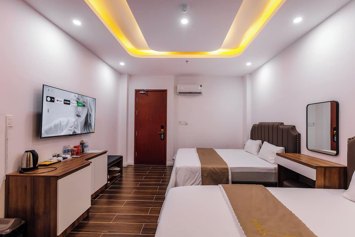 A modern hotel room with a TV, a desk, two beds, and a mirror.