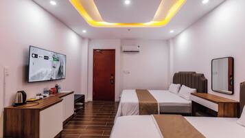 A modern hotel room with a TV, a desk, two beds, and a mirror.