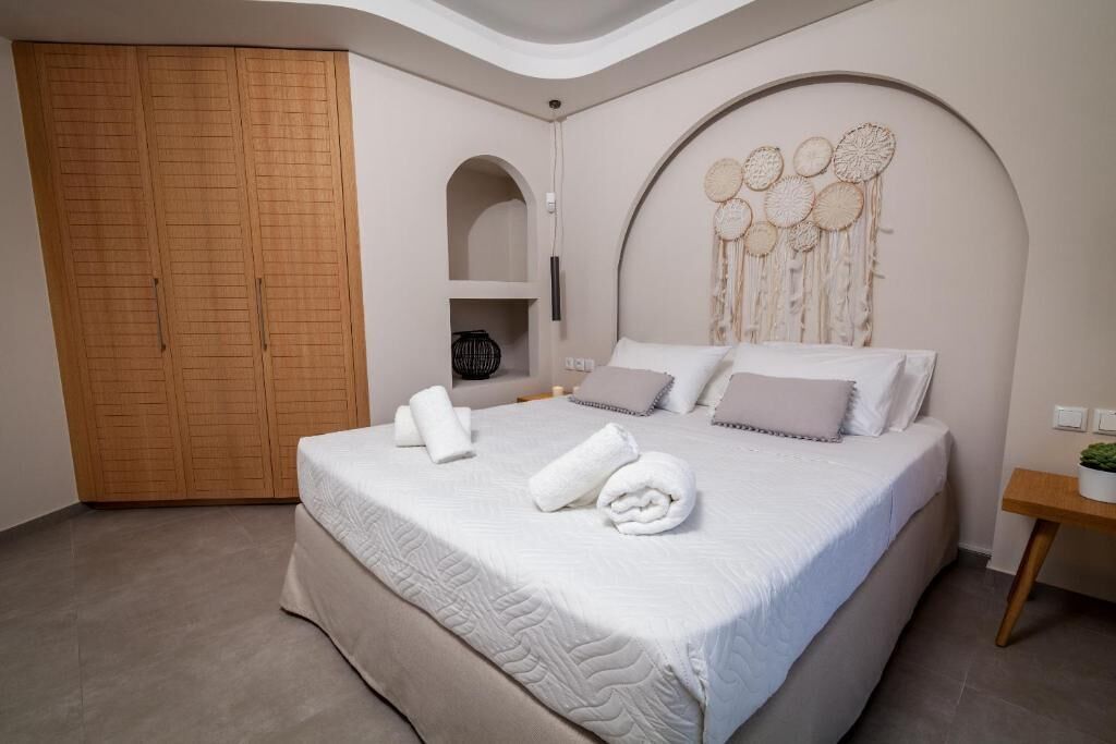 Ein Schlafzimmer mit einem großen Bett, einem Kleiderschrank, einem Schminktisch mit Spiegel und einer Wand mit einem Traumfänger.