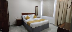 Un dormitorio con cama, mesitas de noche, espejo y ventana con cortinas.