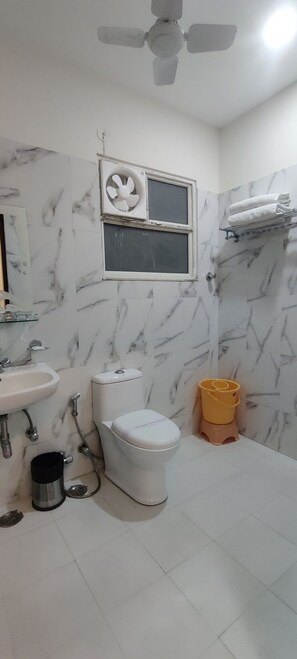 Un baño con inodoro, lavabo y ventilador.
