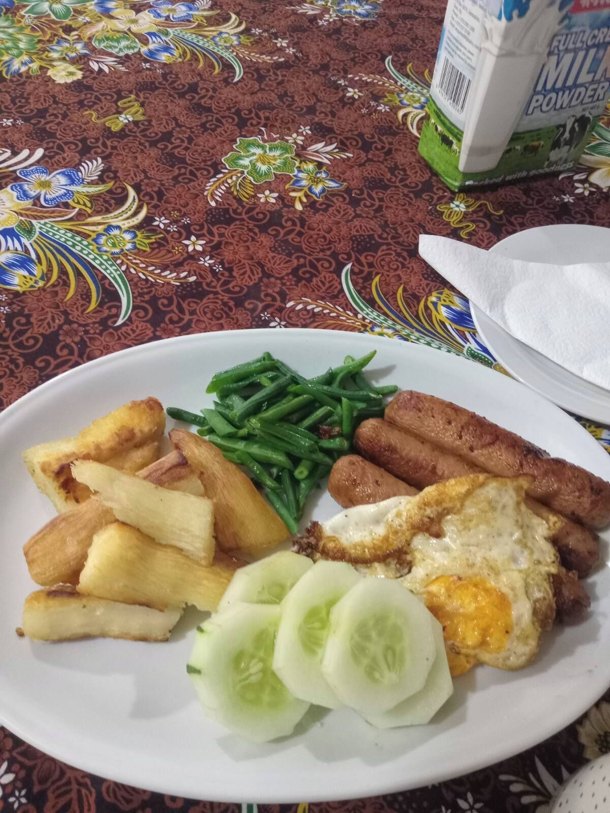 A plate of food with various items including potatoes, green beans, sausages, and a fried egg.