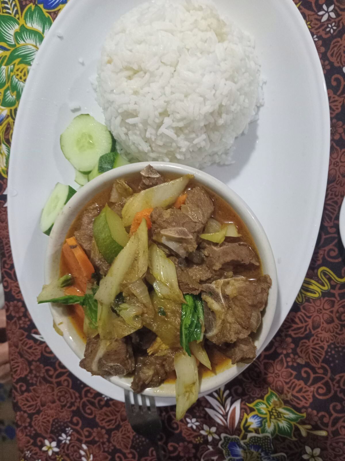 Un plato de arroz blanco y un tazón de guiso de carne con verduras.