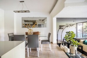 A modern living room with a dining area, a large mirror, and a view of the outdoors.
