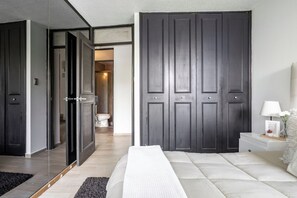 A modern bedroom with a large bed, a bedside table, a nightstand, and a wardrobe.