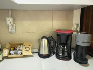 Een keuken met een koffiezetapparaat, een waterkoker en een doos koffiecups.