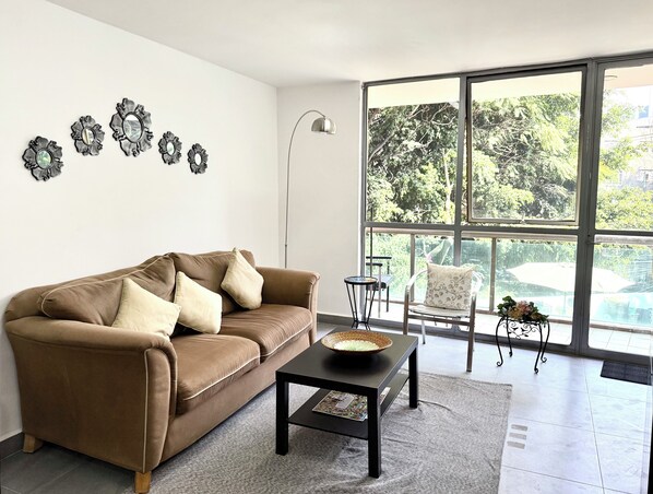 Un salon moderne avec un canapé marron, une petite table et des œuvres d’art décoratives accrochées au mur.